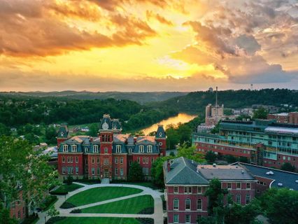 Downtown campus of WVU with sunset in the background over the river